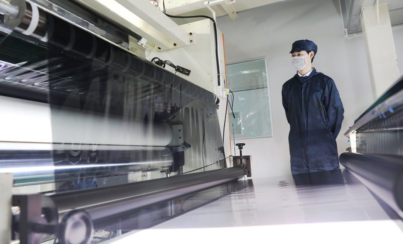 Operator inspecting window film layers on a precision coating line at the KSB factory
